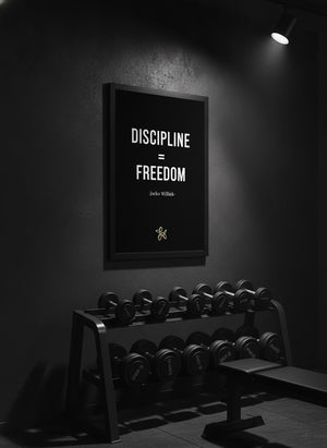 Jocko Willink Discipline Equals Freedom quote canvas in a black frame, hung above a dumbbell rack in a home gym | MusaArtGallery™